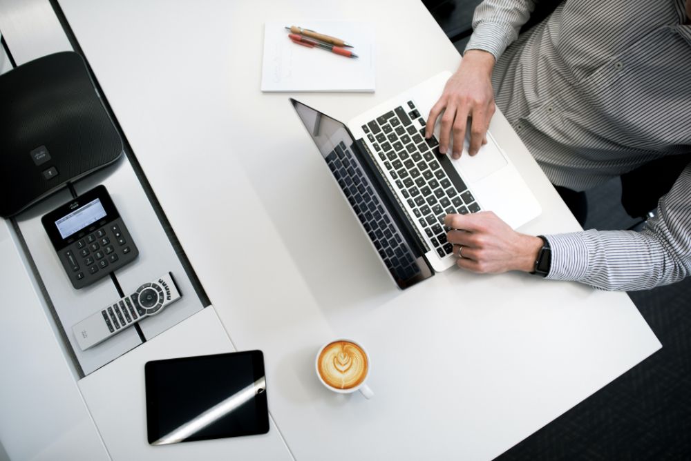 Man using the laptop with coffee and other gadgets